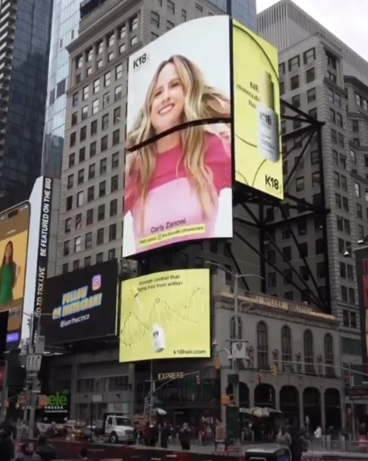 Digital Billboard in Times Square, New York city displaying an advertisement for K18 Hair Oil